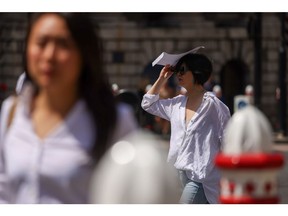 A pedestrian uses an envelope to shade from the sun, in the City of London, UK, on Friday, June 17, 2022. UK temperatures may hit 34 degrees Celsius (93.2 degrees Fahrenheit) this week, a once-rare level that's becoming more common on the back of global warming.