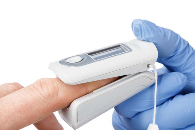 Doctor using pulse oximeter to check oxygen saturation of a person tracking coronavirus symptoms