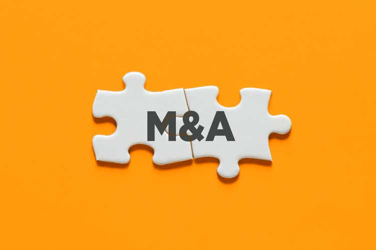 Connected puzzle pieces with the acronym M&A. Merger and acquisition in business