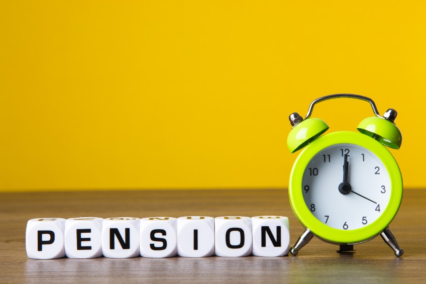 letter blocks that spell pension beside an alarm clock