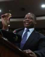 John Mangudya, governor at The Reserve Bank of Zimbabwe, holds a gold coin