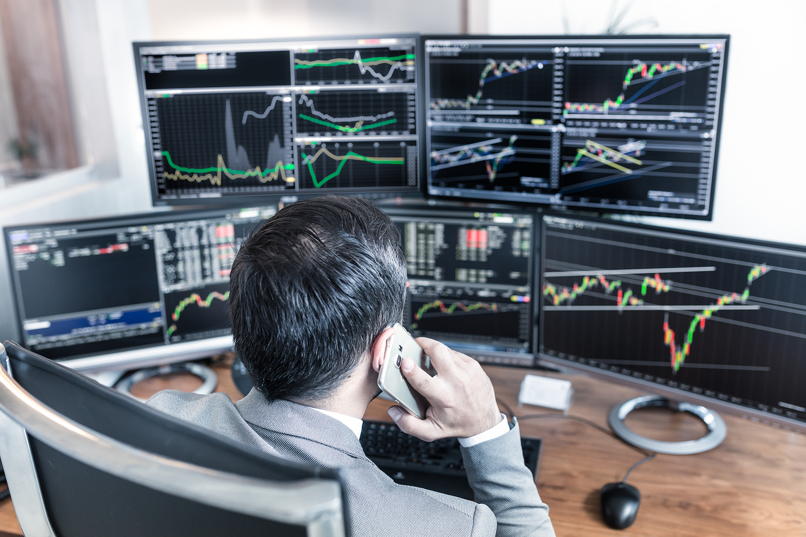 Trader in front of five trading screens
