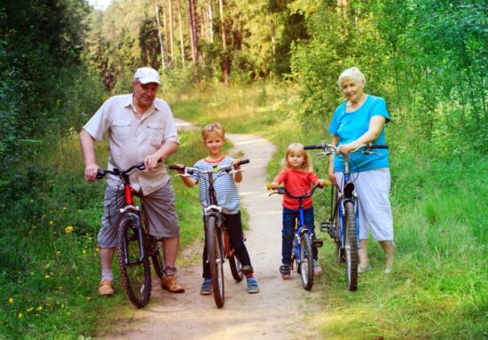 Elderly couple riding bikes with young grandchildren